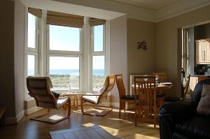 a living room with chairs and a table and windows at Abermaw Sea View Apartment in Barmouth