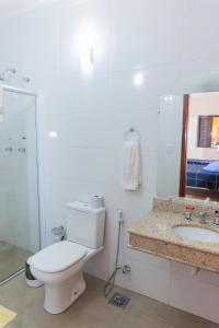 a white bathroom with a toilet and a sink at Hotel Colonial in São Lourenço