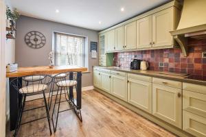 a kitchen with yellow cabinets and a counter with stools at Host & Stay - Lime Tree House in Holme