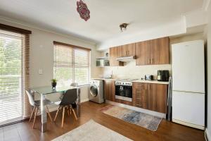 Una cocina con una mesa y un refrigerador blanco. en The Rondebosch Easy Living, en Ciudad del Cabo