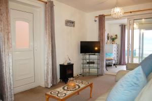 Una sala de estar con un sofá, un televisor y una mesa. en Seagull Beach House, en Tywyn