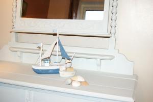 un bote de juguete sentado en un estante bajo un espejo en Seagull Beach House, en Tywyn 31 fotos más