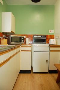 una cocina con estufa y microondas en Seagull Beach House, en Tywyn