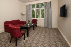 uma sala de estar com um sofá, uma mesa e cadeiras em Holiday Inn - Johannesburg Sunnyside Park, an IHG Hotel em Joanesburgo
