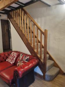 a living room with a red leather couch and stairs at Llugwy Cottage in Betws-y-coed
