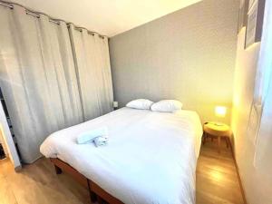 ein Schlafzimmer mit einem weißen Bett mit zwei Handtüchern darauf in der Unterkunft Le bellevue (parking gratuit) in Besançon