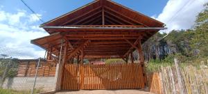 um edifício de madeira com um telhado no topo de uma cerca em CABAÑAS RANCH OXAPAMPA em Oxapampa