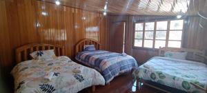 Duas camas num quarto com paredes com painéis de madeira em CABAÑAS RANCH OXAPAMPA em Oxapampa