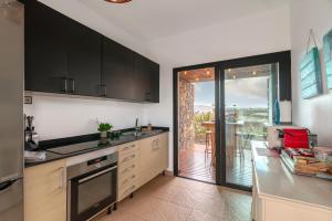 a kitchen with black cabinets and a view of a patio at Villa Shepherd Lajares - LUXURY VILLA FUERTEVENTURA in Lajares