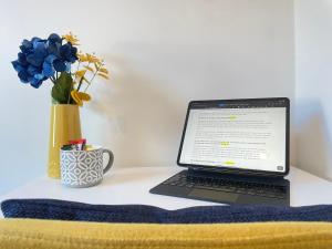een laptop computer op een bureau met een vaas met bloemen bij Sandringham House Serviced Rooms in Hartlepool
