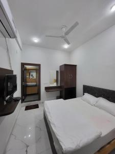 a bedroom with a white bed and a tv at AMALTAAS HOMESTAY in Gwalior