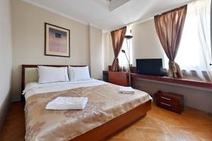 a bedroom with a large bed and a television at Sole Mio Wellness & SPA in Novi Sad