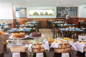 een kamer gevuld met tafels en stoelen met gebak en gebak bij Sonia Flats Natal - No Apart Hotel Ponta Negra Beach in Natal