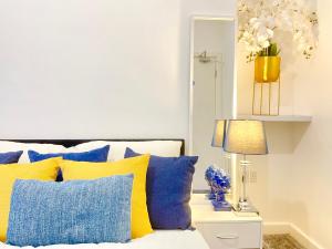 Schlafzimmer mit einem Bett mit blauen und gelben Kissen in der Unterkunft Sandringham House Serviced Rooms in Hartlepool