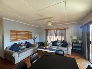 a living room with two couches and a table at Loddeys Beach House in Strand