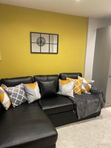 a black leather couch with colorful pillows in a room at 2 Bedroom House & Parking 2 washrooms in Reading