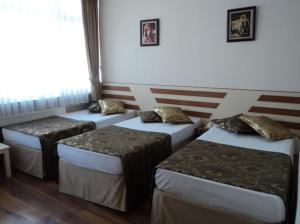 three beds in a room with a flag on the wall at Tac Hotel in Ankara