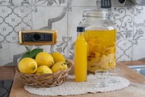 uma tigela de limões, uma garrafa de sumo de laranja e uma cesta de frutas. em La Casa nel Cortile em Vico Equense