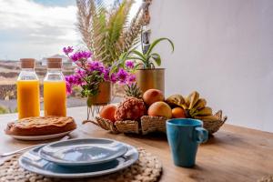 a table with a basket of fruit and orange juice at Villa Shepherd Lajares - LUXURY VILLA FUERTEVENTURA in Lajares