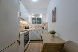 a small kitchen with white cabinets and a table at Kallithea Gardenspot in Athens