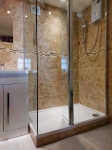 a shower with a glass door in a bathroom at High View Studio with terrace & sea views in Barmouth