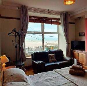 a bedroom with a bed and a couch and a window at High View Studio with terrace & sea views in Barmouth