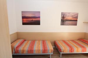 2 Betten in einem Zimmer mit 2 Gemälden an der Wand in der Unterkunft Tamerici in Bibione