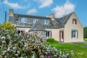 een huis met een stenen schoorsteen op een gazon bij La maison de la petite lande in Saint-Jean-du-Doigt