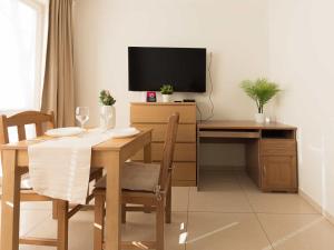 a dining room with a table and a desk with a television at VacationClub - Planeta Apartament 112 in Mielno