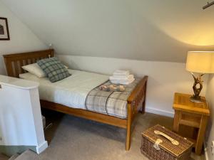 een slaapkamer met een bed en een tafel met een lamp bij Rosemount Bothy - Highland Cottage in Garve