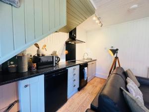 een woonkamer met een bank en een keuken bij Rosemount Bothy - Highland Cottage in Garve