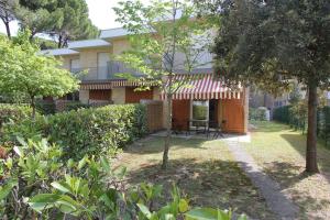 ein Haus mit roter Markise im Hof in der Unterkunft Tamerici in Bibione