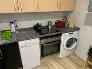 a kitchen with a stove top oven next to a washing machine at Apartamento completo para 8 personas a 5 minutos del aeropuerto e IFEMA in Madrid