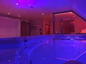 een groot bad in een kamer met paarse verlichting bij Aarts Wellness in As