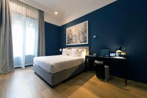 a bedroom with a bed and a desk with a blue wall at Elizabeth Unique Hotel | a Member of Design Hotels™ in Rome
