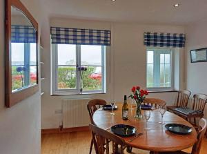 uma sala de jantar com mesa, cadeiras e janelas em Garreg Wen - White Stone, family holiday home em Barmouth