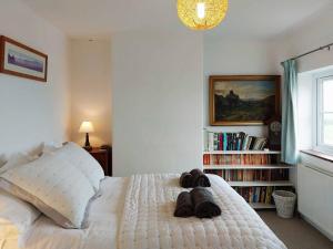 um quarto com uma cama branca com sapatos em Garreg Wen - White Stone, family holiday home em Barmouth