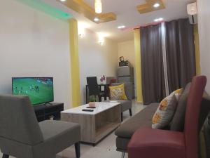 sala de estar con TV, sofá y sillas en HOTEL APPART B4U - BE FOR YOU, en Yaoundé