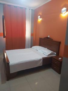 a bedroom with a large bed and a night stand at HOTEL APPART B4U - BE FOR YOU in Yaoundé