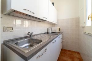 een keuken met een roestvrijstalen wastafel en witte kasten bij La Casa dei Mori - Ortigia Central Apartment in Siracusa
