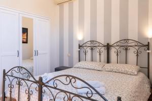 een slaapkamer met een metalen bed met gestreepte muren bij La Casa dei Mori - Ortigia Central Apartment in Siracusa
