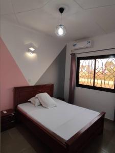 a bedroom with a large white bed with a window at HOTEL APPART B4U - BE FOR YOU in Yaoundé