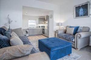 a living room with a couch and a blue ottoman at Pencw Garden View - 3 Bed Apartment - Saundersfoot in Saundersfoot
