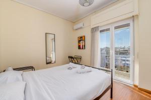 a bedroom with a white bed and a large window at Marina Zeas Bella Vista in Piraeus