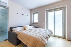 1 dormitorio con 1 cama grande y reloj en la pared en La Casa Nelle Aie - App. Nebbiolo -Box Auto & WiFi, en La Morra