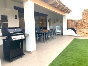 eine Terrasse mit einem Grill, einem Tisch und Stühlen in der Unterkunft Can Roig in Ses Salines