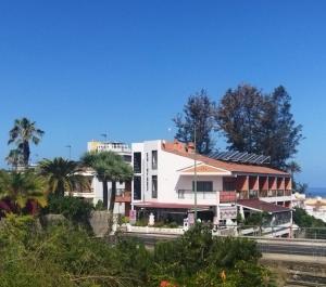 プエルト・デ・ラ・クルスにあるApartamentos Chinyeroのヤシの木と海の白い建物