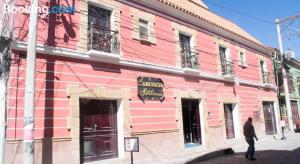 a man standing outside of a pink building at HOTEL SAMARICUSUN in Potosí