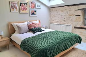 een slaapkamer met een groot bed en een groene deken bij In the heart of the village - Charming & Authentic in Monpazier