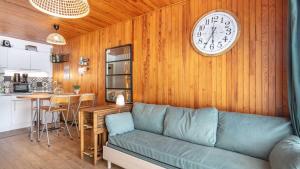 ein Wohnzimmer mit einem Sofa und einer Uhr an der Wand in der Unterkunft Le Carina -4- charmant Studio 4 pers in Chamrousse